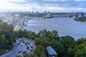 A vibrant skyline and river view of Kyiv, Ukraine, showcasing urban architecture and traffic.